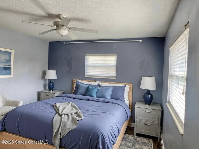 bedroom with ceiling fan, dark wood-type flooring, and a textured ceiling