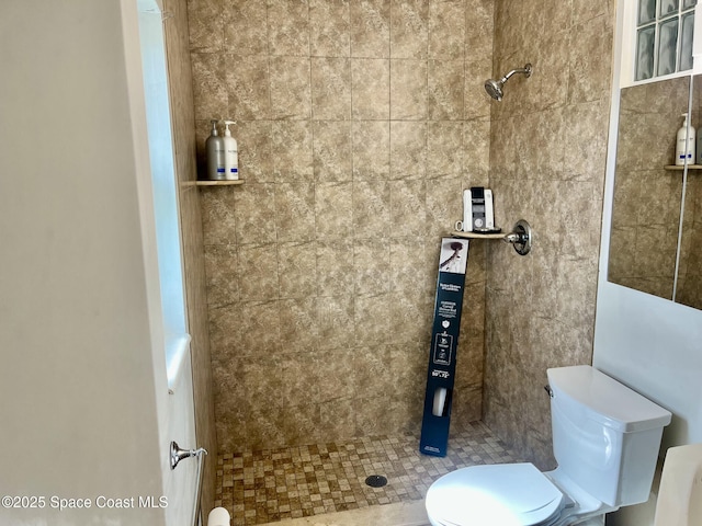 bathroom featuring tiled shower and toilet