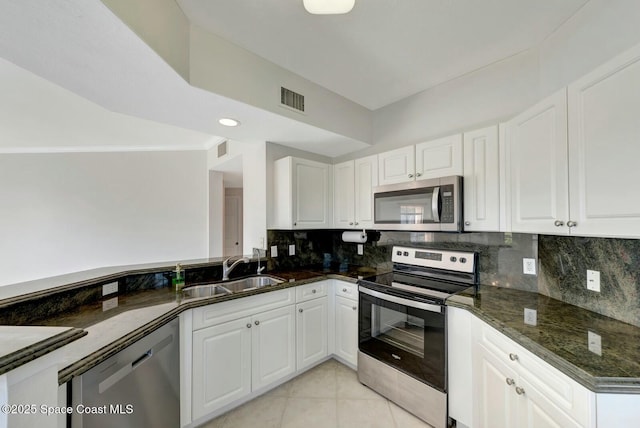 kitchen featuring stainless steel appliances, white cabinetry, sink, and dark stone counters