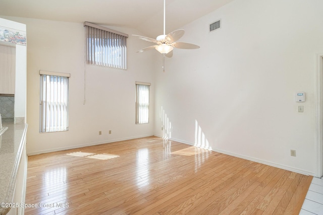 unfurnished living room with ceiling fan, high vaulted ceiling, and light hardwood / wood-style flooring