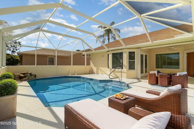 view of swimming pool featuring ceiling fan, an outdoor hangout area, a patio area, and glass enclosure