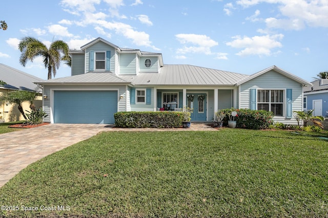 traditional home with decorative driveway, a porch, metal roof, a front yard, and a garage