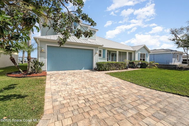 view of front of property with a standing seam roof, an attached garage, a front lawn, decorative driveway, and metal roof