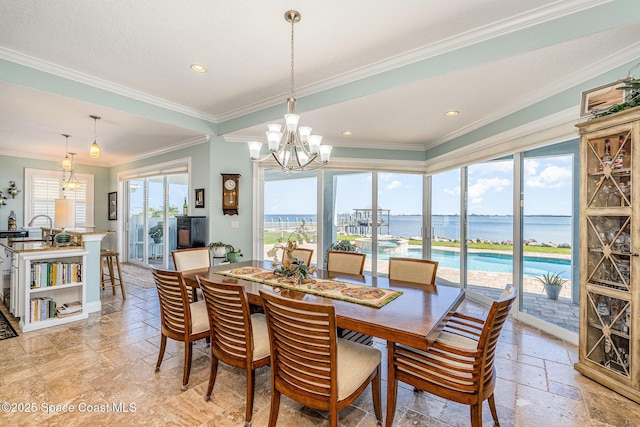 dining room featuring ornamental molding, a water view, and an inviting chandelier