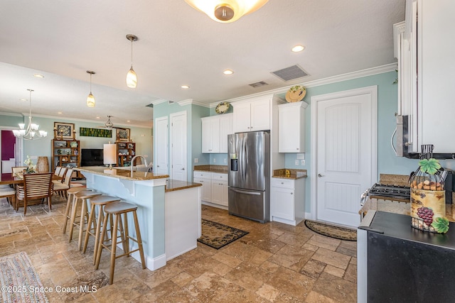 kitchen with appliances with stainless steel finishes, a kitchen bar, a kitchen island with sink, and white cabinets