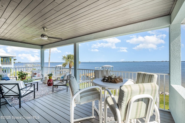 wooden deck with outdoor lounge area, ceiling fan, and a water view