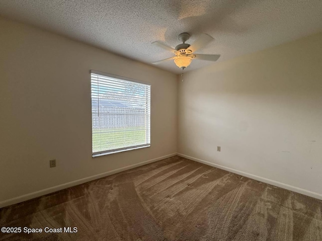 empty room with ceiling fan, dark carpet, and a textured ceiling