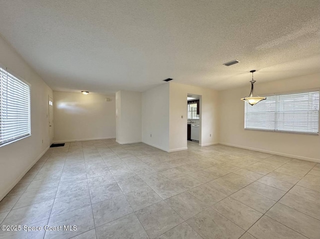 tiled empty room featuring a healthy amount of sunlight and a textured ceiling