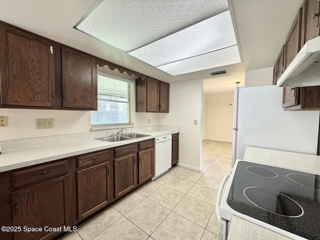 kitchen with sink, white appliances, dark brown cabinets, and light tile patterned flooring