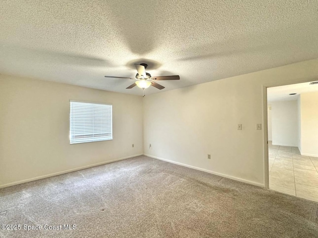 empty room with ceiling fan, light colored carpet, and a textured ceiling