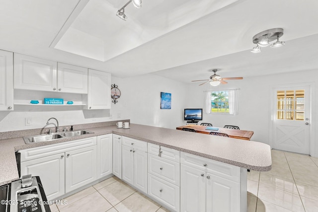 kitchen featuring sink, light tile patterned floors, kitchen peninsula, ceiling fan, and white cabinets