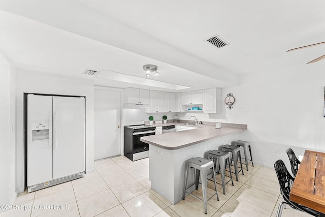 kitchen with sink, appliances with stainless steel finishes, white cabinetry, a kitchen bar, and kitchen peninsula