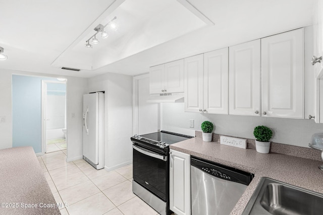 kitchen with light tile patterned floors, stainless steel appliances, a raised ceiling, and white cabinets