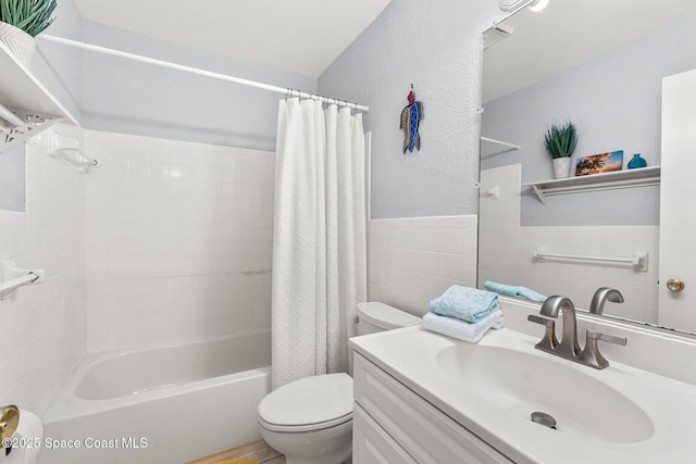 full bathroom featuring shower / bath combination with curtain, vanity, toilet, and tile walls