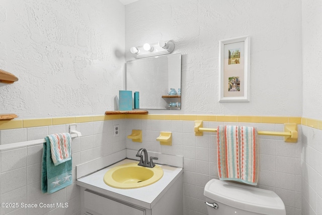 bathroom featuring vanity, tile walls, and toilet