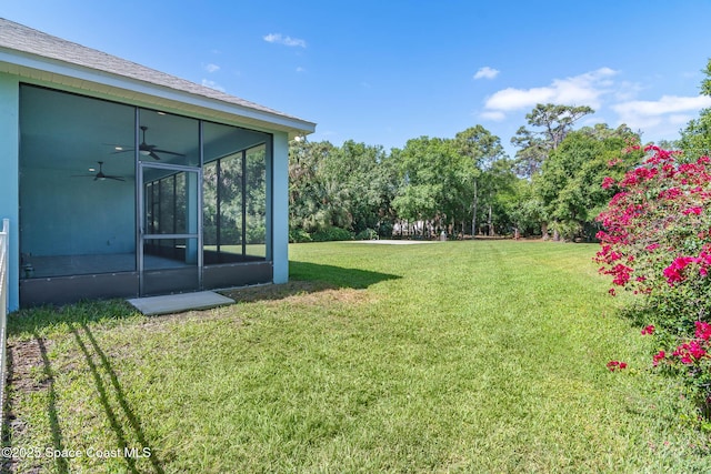 view of grassy yard with a sunroom and a ceiling fan