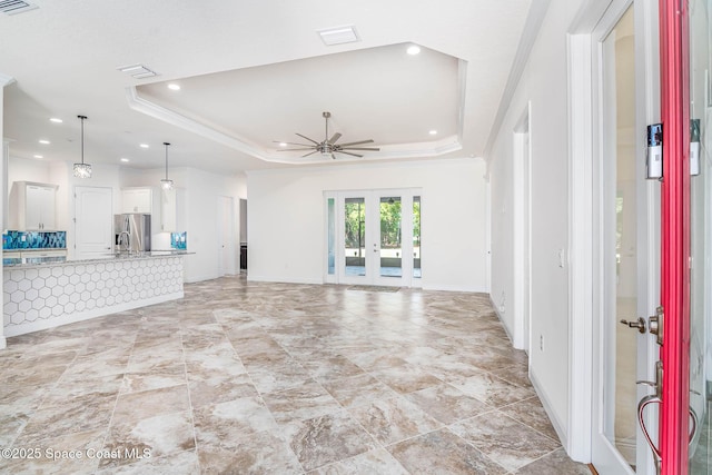unfurnished living room featuring a tray ceiling, french doors, a ceiling fan, baseboards, and recessed lighting