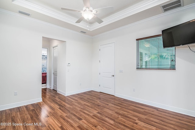 spare room with wood finished floors, crown molding, baseboards, ceiling fan, and a raised ceiling