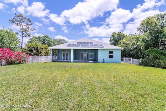 rear view of house featuring ceiling fan, a sunroom, roof mounted solar panels, stucco siding, and roof with shingles