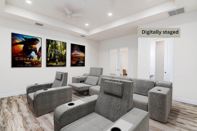 home theater room featuring light wood finished floors, a raised ceiling, ceiling fan, baseboards, and french doors