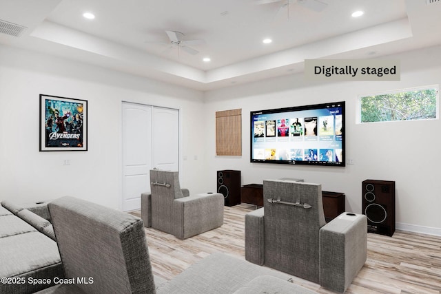 cinema room featuring ceiling fan, light wood-style flooring, a tray ceiling, and recessed lighting