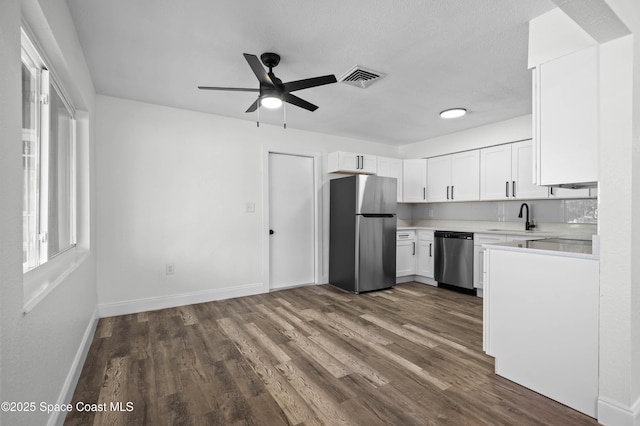 kitchen featuring dark wood-type flooring, sink, appliances with stainless steel finishes, ceiling fan, and white cabinets