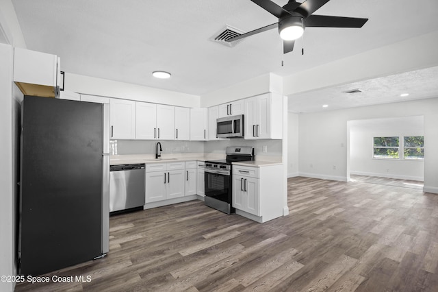 kitchen featuring appliances with stainless steel finishes, dark hardwood / wood-style flooring, sink, and white cabinets