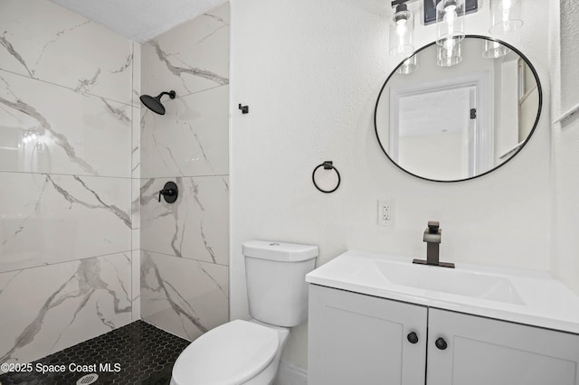 bathroom with vanity, toilet, and tiled shower