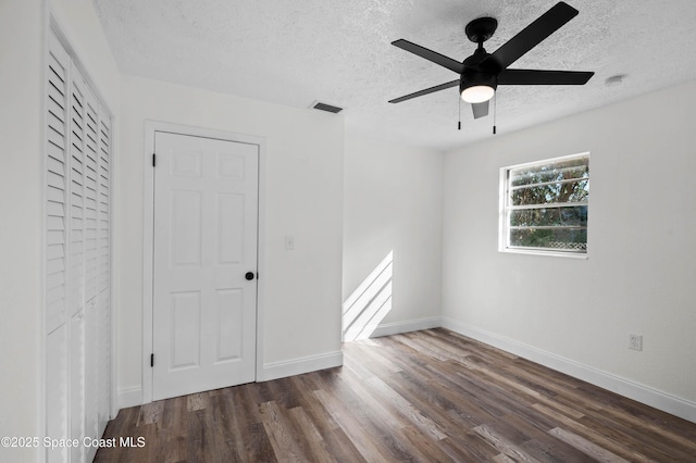 unfurnished bedroom featuring ceiling fan, dark hardwood / wood-style flooring, and a textured ceiling