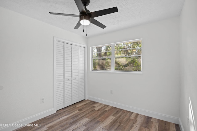 unfurnished bedroom with wood-type flooring, ceiling fan, a textured ceiling, and a closet