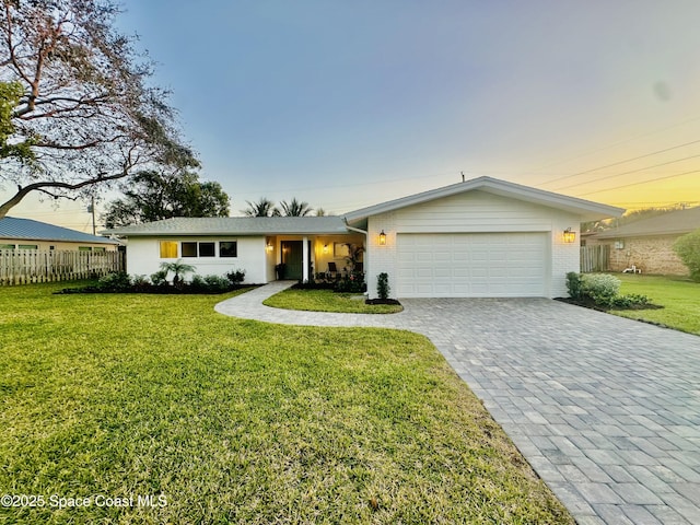 ranch-style home featuring a garage and a lawn