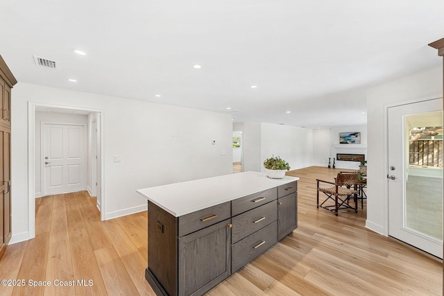 kitchen with dark brown cabinets, a kitchen island, and light wood-type flooring