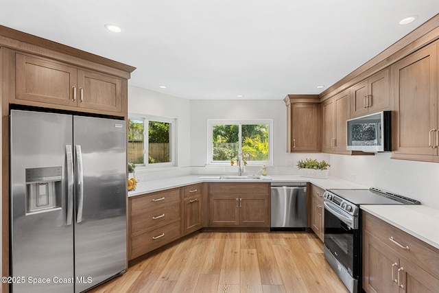 kitchen with stainless steel appliances, sink, and light wood-type flooring