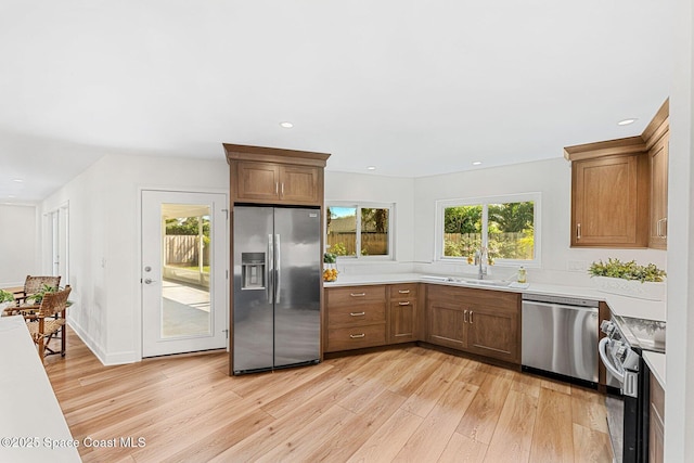 kitchen with a healthy amount of sunlight, appliances with stainless steel finishes, sink, and light hardwood / wood-style floors