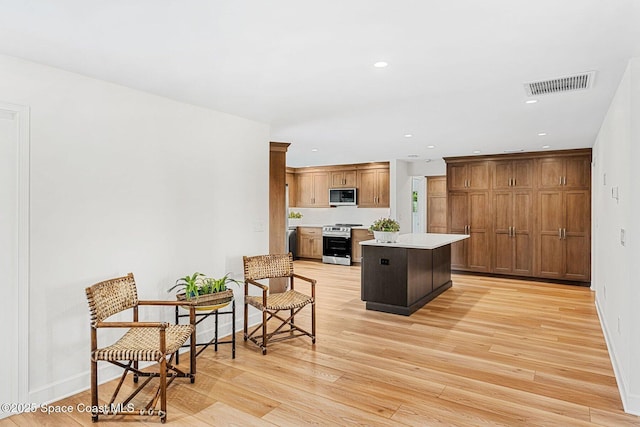 kitchen featuring a center island, stainless steel range, light hardwood / wood-style floors, and a breakfast bar