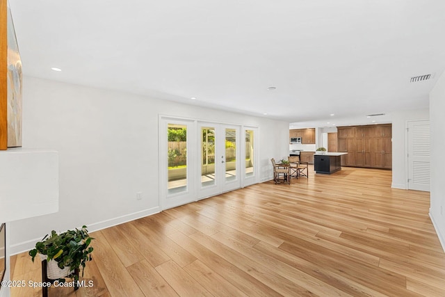 unfurnished living room featuring french doors and light hardwood / wood-style flooring