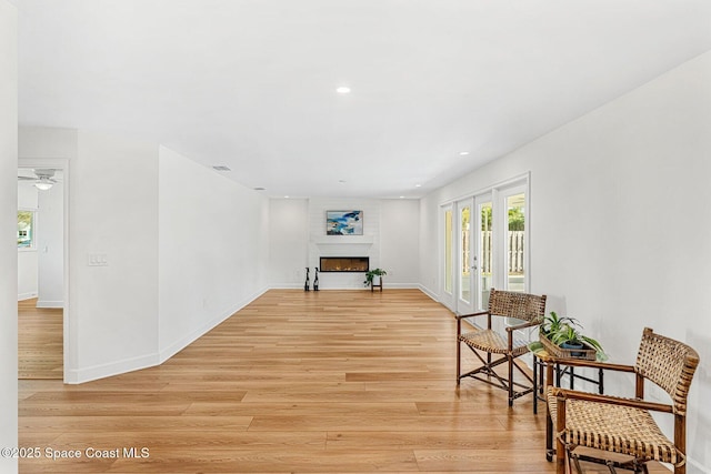 living area featuring a large fireplace, light hardwood / wood-style floors, and french doors