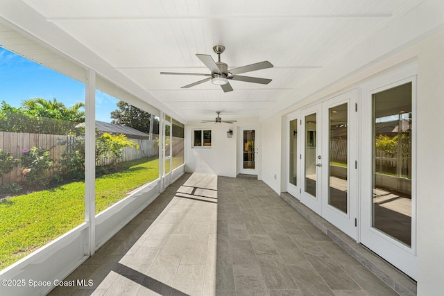 unfurnished sunroom featuring ceiling fan, french doors, and a healthy amount of sunlight