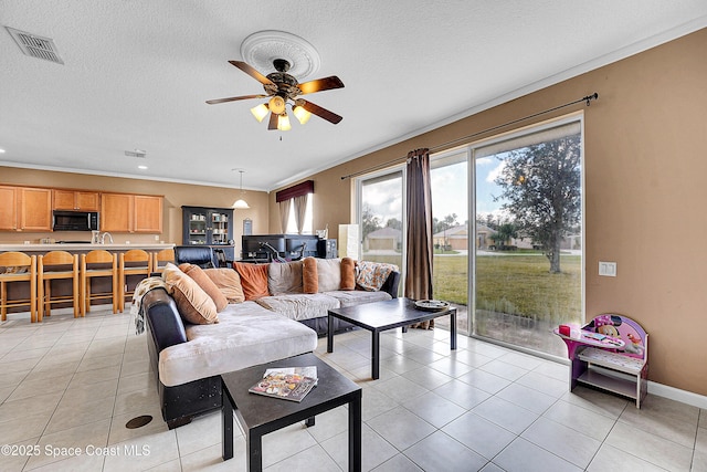 tiled living room with crown molding, ceiling fan, and a textured ceiling