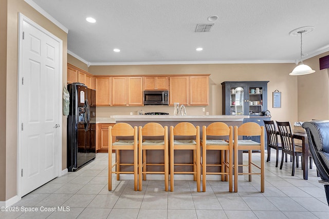 kitchen with a breakfast bar, a center island with sink, decorative light fixtures, black refrigerator with ice dispenser, and light brown cabinets