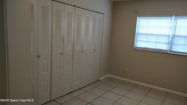 unfurnished bedroom with light tile patterned flooring and a closet