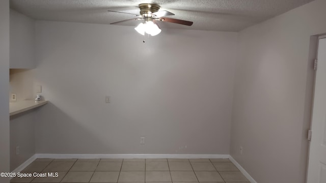 interior space featuring ceiling fan, light tile patterned floors, and a textured ceiling