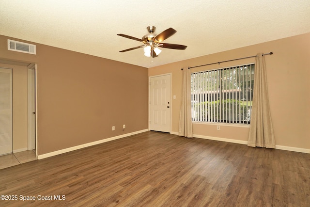 spare room with baseboards, visible vents, and dark wood-type flooring