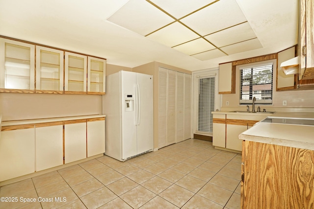 kitchen featuring light tile patterned floors, white refrigerator with ice dispenser, ventilation hood, light countertops, and a sink