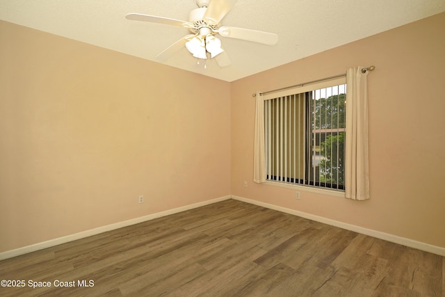 unfurnished room featuring a ceiling fan, baseboards, and wood finished floors