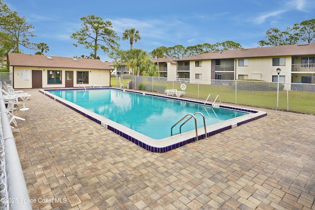 pool with a patio, a yard, and fence