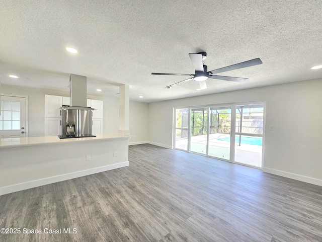 unfurnished living room with hardwood / wood-style flooring, ceiling fan, and a textured ceiling