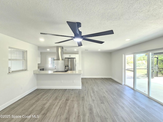 unfurnished living room featuring ceiling fan, light hardwood / wood-style floors, and a textured ceiling