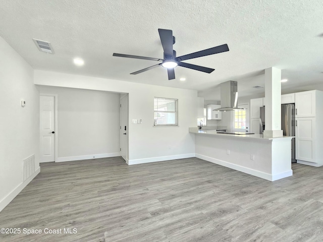 unfurnished living room featuring ceiling fan, a textured ceiling, and light hardwood / wood-style floors