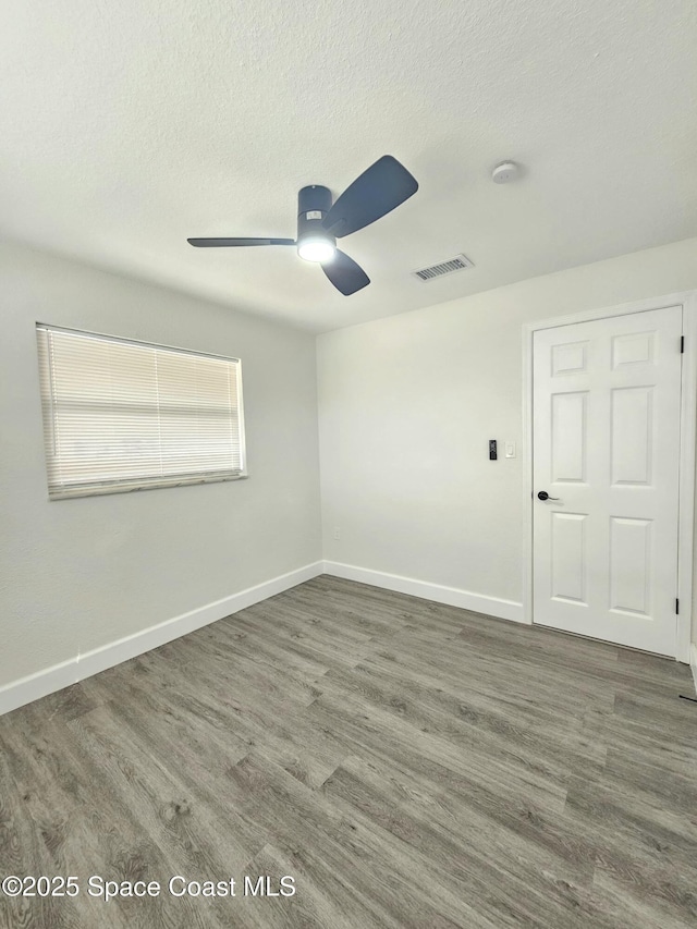 empty room with ceiling fan, dark hardwood / wood-style flooring, and a textured ceiling